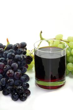 a glass of grape juice with a light and dark grapes