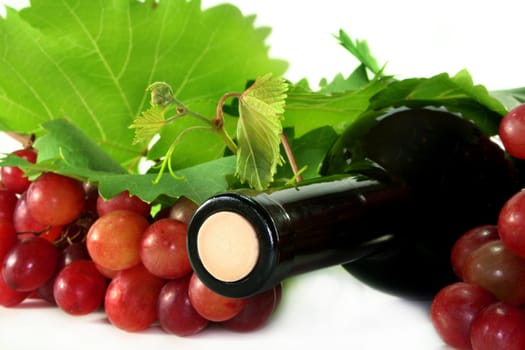 A bottle of red wine with grapes and leaves