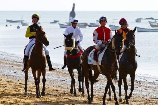 SANLUCAR DE BARRAMEDA, CADIZ, SPAIN - AUGUST 10: Unidentified riders at the start of race horses on Sanlucar de Barrameda beach on August 10, 2011 in Sanlucar de Barrameda, Cadiz, Spain.