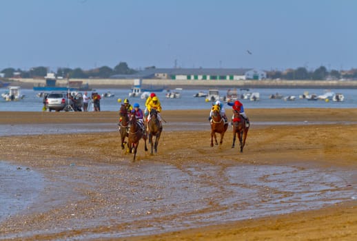 SANLUCAR DE BARRAMEDA, CADIZ, SPAIN - AUGUST 11: Unidentified riders race horses on Sanlucar de Barrameda beach on August 11, 2011 in Sanlucar de Barrameda, Cadiz, Spain.