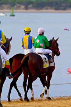 SANLUCAR DE BARRAMEDA, CADIZ, SPAIN - AUGUST 11: Unidentified riders at the start of race horses on Sanlucar de Barrameda beach on August 11, 2011 in Sanlucar de Barrameda, Cadiz, Spain.