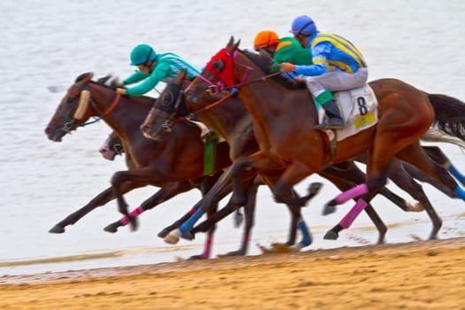 SANLUCAR DE BARRAMEDA, CADIZ, SPAIN - AUGUST 11: Unidentified riders race horses on Sanlucar de Barrameda beach on August 11, 2011 in Sanlucar de Barrameda, Cadiz, Spain.