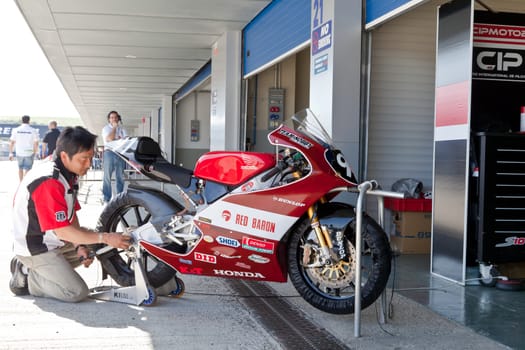JEREZ DE LA FRONTERA, SPAIN - APR 17: 125cc Motorcycle of Mori Syunya in the pitlane being reparing by a mechanic in the CEV Championship on April 17, 2011, in Jerez de la Frontera, Spain.