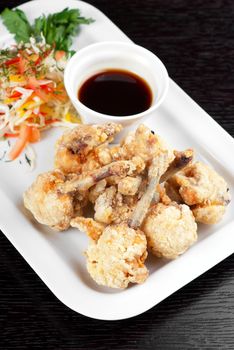 Fried chicken wings garnished with fresh vegetables with Teriyaki sauce