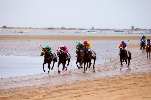 SANLUCAR DE BARRAMEDA, CADIZ, SPAIN - AUGUST 07: Unidentified riders race horses on Sanlucar de Barrameda beach on August 07, 2010 in Sanlucar de Barrameda, Cadiz, Spain.