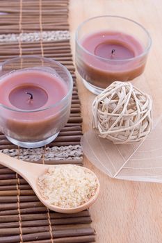 Salt in wooden spoon and other spa products with candles