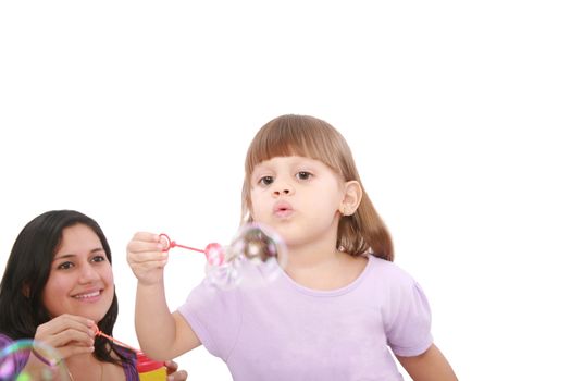 Portrait of funny lovely little girl blowing soap bubbles with her mom. Little girl on focus.