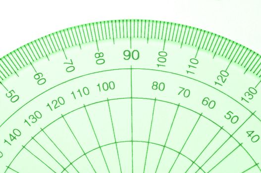 Close Up capturing a portion of a transparent plastic protractor arranged over white.
