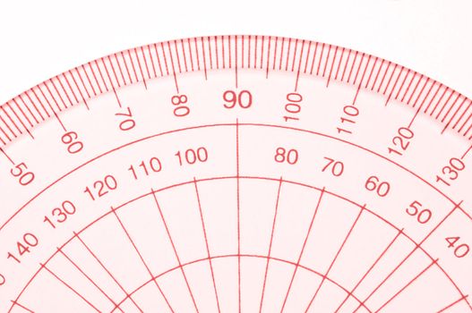 Close Up capturing a portion of a transparent plastic protractor arranged over white.