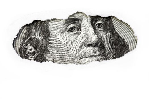 Benjamin Franklin macro peeking through torn white paper.