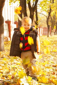 Boy playing with leaves at fall time