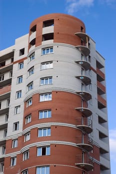 Modern multistory house of red and white bricks on  blue sky background