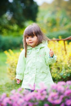 Clouse-up portrait pretty little girl in the park with a flower