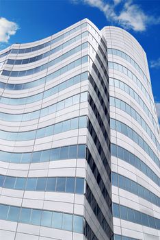 Futuristic corporate building with blue sky reflected in windows