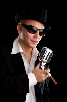 Singer with old fashioned mic and black hat
