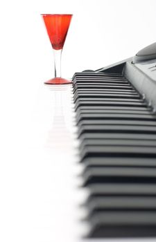 Piano keyboard and red glass on isolated background