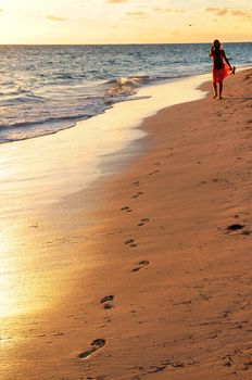 Woman walking on tropical beach at sunrise