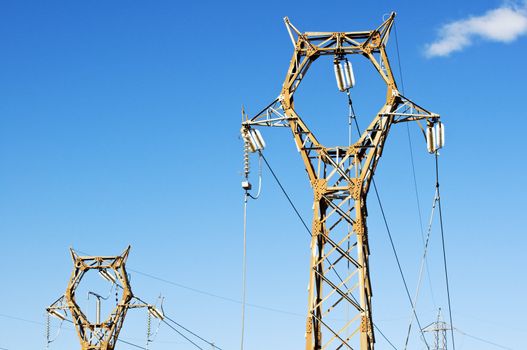 High voltage pylons against blue sky
