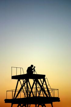 photographer silhouette on tower against evening dusk gradient sky