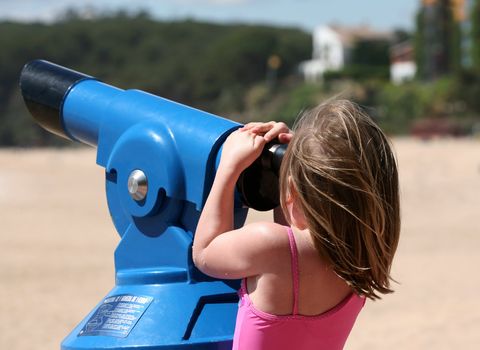 The little girl looks in a telescope