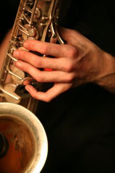 Hands of the saxophonist with a saxophone on a black background
