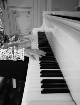 The image of the piano and child's hands. b/w