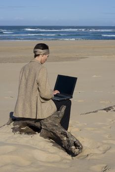 Young professional working on his laptop at the beach