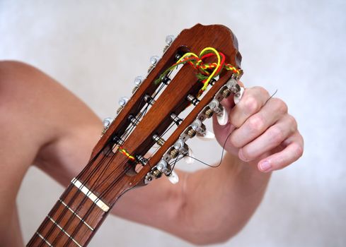 The man's hand adjusts a guitar