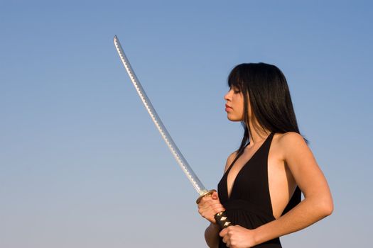 Asian model posing with a sword against blue sky