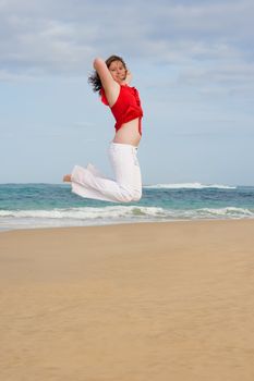 Jumping for joy on the beach wearing red and white