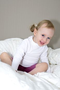 little girl sitting on a bed and smiling