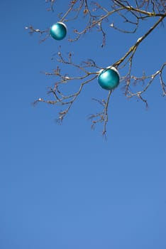 New year toy hanging on a tree without leaves branches on background of blue sky.