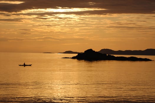 A lone canoeist at sunset from the shoreline at Arisaig, Scotland