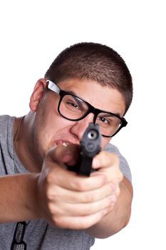 An angry looking teenager wearing black frame glasses points a black handgun at the viewer. Shallow depth of field with focus on the face.
