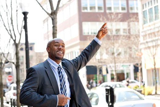 An African American business man raises his hand to hail a cab in the city.