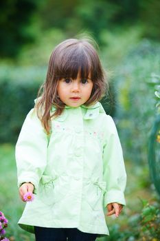 Clouse-up portrait pretty little girl in the park with a flower