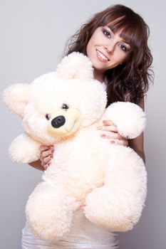 beautiful girl with a teddy bear on a gray background