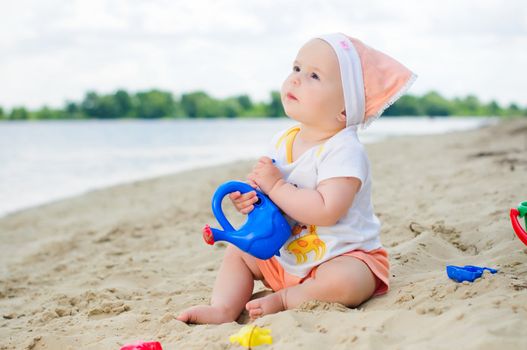 cute baby girl playing on the beach with sand.