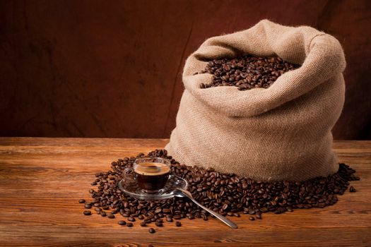 Studio photo of sack with scattered coffee grain, and cup of espresso