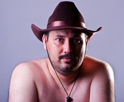 Portrait of the unshaven man in a hat in studio