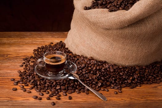 Studio photo of sack with scattered coffee grain, and cup of espresso