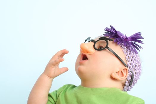 Funny baby wearing toy glasses and headband