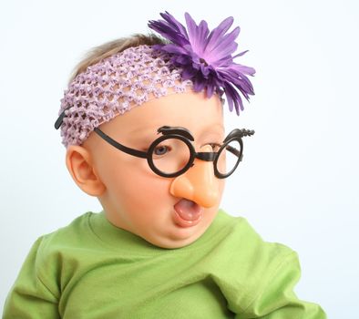 Funny baby wearing toy glasses and headband