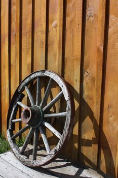 Abandoned wagon wheel against a wooden wall