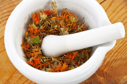 white mortar with dry marigold flower on wooden background