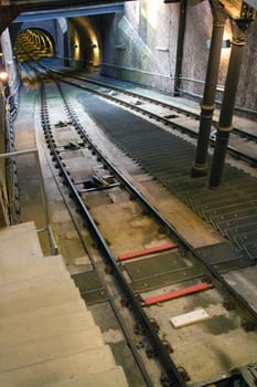 Two railway tracks follow the steep gradient to a tunnel passing underground.