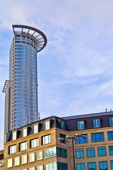 A skyscrapper stands tall behind an office building in Europe.
