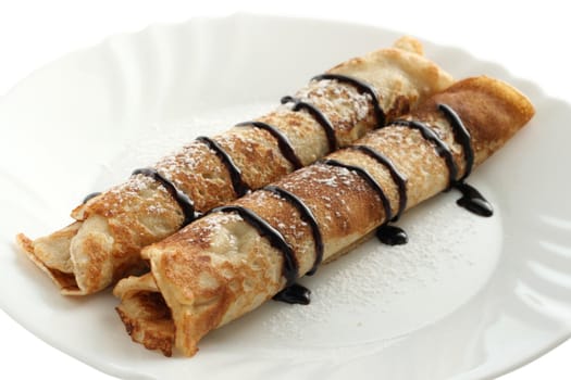 rolled pancakes with chocolate sauce on plate