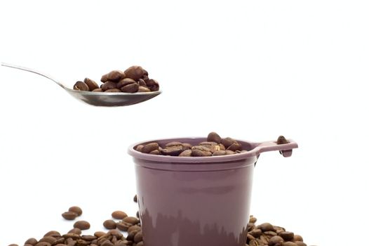 Cup, spoon with coffee beans on white