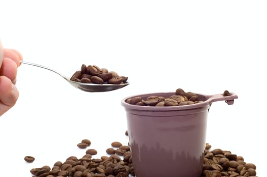 Hand with spoon. Cup with coffee beans on white
